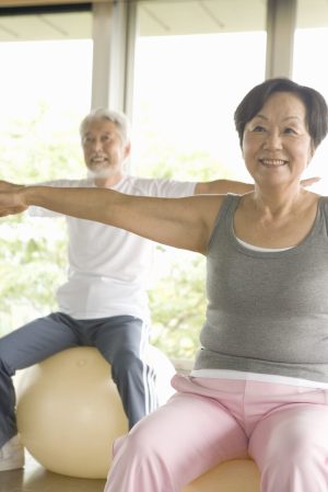 Senior couple stretching on exercise balls, smiling